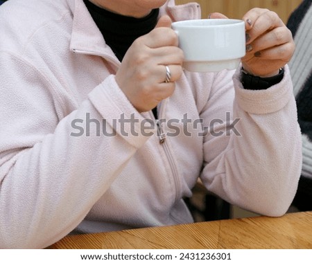 Caucasian woman holding a cup of tea at the wooden table. Shallow depth field.