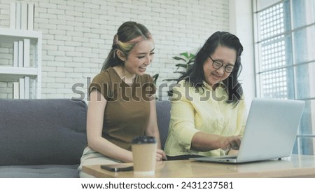 Asian mother and daughter working on computer together at home
