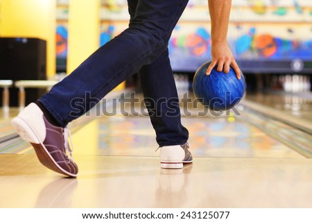 Male legs and bowling ball in alley background