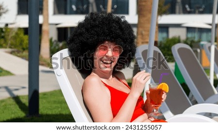Cheerful woman with a toothy smile with a cocktail a sun lounger.