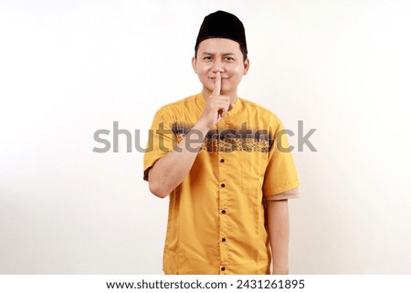 Young asian man wearing typical muslim clothes isolated on white background keeping a secret or asking for silence.