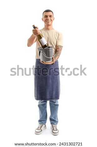 Young male bartender with bottle of champagne on white background