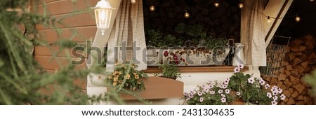Cozy window, adorned with flowers, illuminated by string lights. Wooden GARDEN sign adds rustic touch. Concept: home decor, gardening inspiration. Banner with copy space.