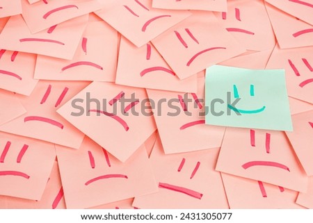 One paper sheet with drawn happy face among sheets with sad ones. Concept of uniqueness