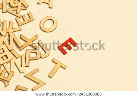 One red letter among wooden ones on light background. Concept of uniqueness
