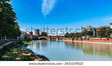 Italy.Verona.View of the Adige river.The Scaliger Bridge and Castelvecchio Castle are visible in the distance.Blue sky with white clouds.Copy space. Royalty-Free Stock Photo #2431319023