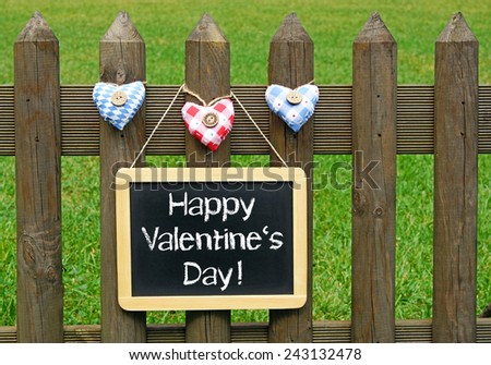 Happy Valentines Day - blackboard with three hearts on garden fence