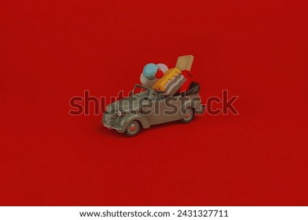 Little vintage car with gifts on red background. Concept of receiving profit and benefit