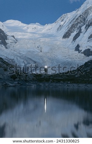 moody night picture of man standing in front of glacier, switzerland