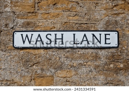 Old road sign Road Sign on a yellow brick wall giving its location as "Wash Lane."