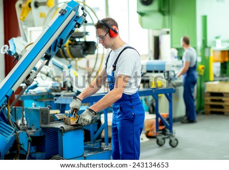 worker in protective clothing in factory using machine