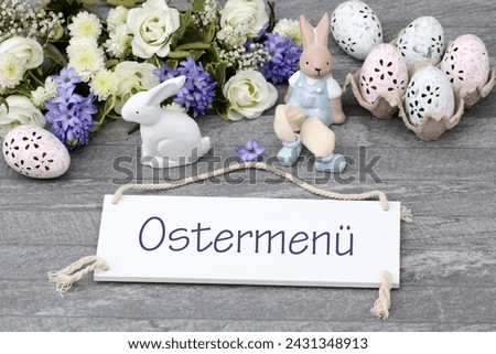 Flowers with Easter eggs and the text Easter menu on a blackboard. German inscription translates as Easter menu.