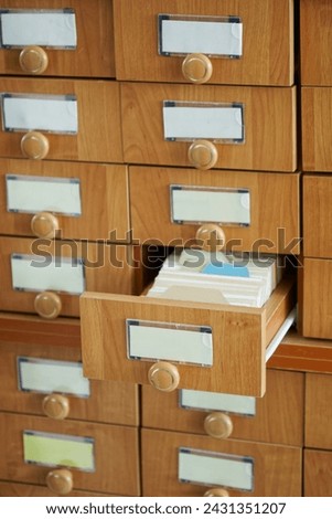 Open wooden file cabinet drawer with lots of paper cards. Vintage storage of information and data Place for inscription - mockup. Photo. Selective focusing. Natural lighting Royalty-Free Stock Photo #2431351207
