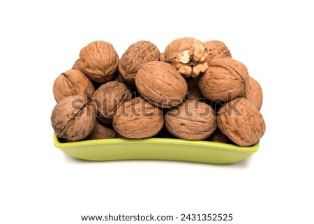 Fresh, Uncracked Walnuts Nestled in a Vibrant Green Bowl, This image beautifully captures fresh, uncracked walnuts nestled in a sleek, vibrant green bowl. The earthy brown tones of the walnuts