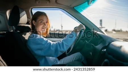 young woman driver driving a car on a sunny day.