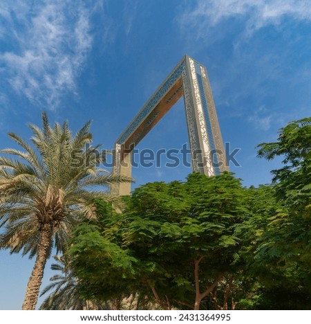 A picture of the Dubai Frame above the trees of the Zabeel Park.