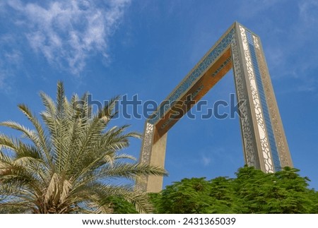 A picture of the Dubai Frame above the trees of the Zabeel Park.