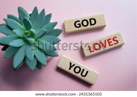 God loves you symbol. Wooden blocks with words God loves you. Beautiful pink background with succulent plant. Religion and God loves you concept. Copy space.
