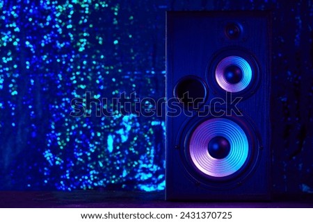 Sound speaker in neon light. Modern hi-fi loudspeaker against black background. Sound audio speaker with neon lights. Dynamic sub monitor close up. Creative background