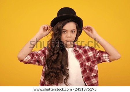 Child girl in magician hat, cylinder hat isolated on yellow background. Headwear. Clothes accessories. Fashion headwear for gentlemen in vintage style, old classic cylinder. Royalty-Free Stock Photo #2431375195