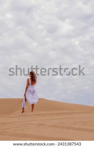 Graceful model embraces nature's beauty in the sand dunes, epitomizing elegance against the backdrop of vast, natural splendor
