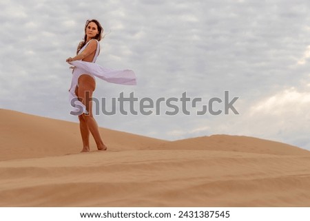 Graceful model embraces nature's beauty in the sand dunes, epitomizing elegance against the backdrop of vast, natural splendor