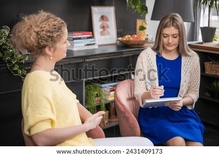 A coaching Mentor in yellow sweater guiding client, pen in hand, in a supportive psychotherapy environment, business and self growth session. High quality photo