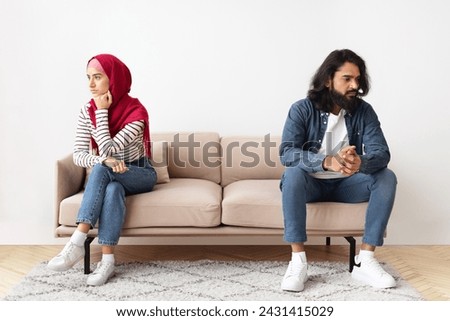 Relationship Crisis. Young Muslim Husband And Wife Offended To Each Other After Argue, Grumpy Arabic Spouses Sitting On Couch Back To Back, Married Couple Angry After Domestic Quarrel, Free Space Royalty-Free Stock Photo #2431415029