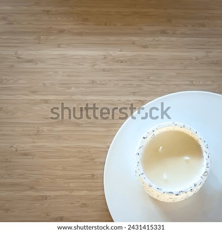Top view of a white candle on a ceramic plate on a wooden table with copy space