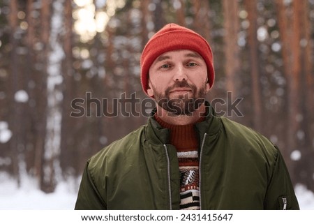 Portrait of young Caucasian man wearing warm clothes standing in forest on winter day