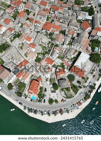Drone picture of a tiny semi-island with white houses and red roofs somewhere in the Adriatic sea