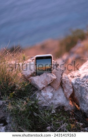 phone records timelapse video shoots sunset on the sea instead of a tripod used rocks around nature cliff rocks and the Adriatic sea, on the screen of the phone sea sunset