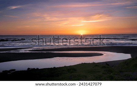 Sundown on California's scenic Central Coast. Water flowing into the ocean is from inland streams overflowing from heavy winter rains Royalty-Free Stock Photo #2431427079
