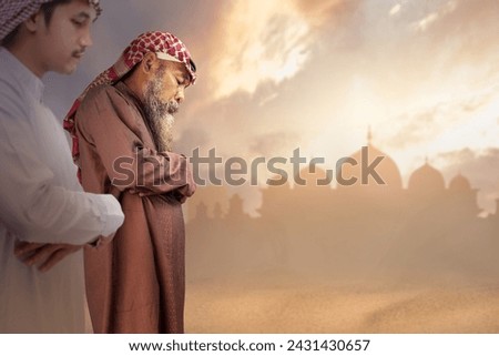 Two Muslim men with agal in a praying position (salat) with a dramatic sky background. Muslim concept Royalty-Free Stock Photo #2431430657