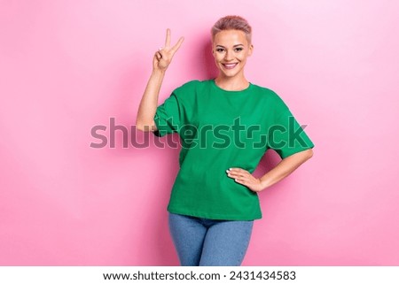 Photo of lovely positive girl beaming smile demonstrate v-sign empty space isolated on pink color background