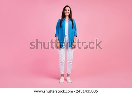 Full size photo of good mood confident girl dressed blue shirt white trousers standing look at camera isolated on pink color background