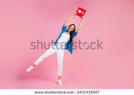Full size photo of funny funky girl dressed blue shirt white trousers holding like icon over head isolated on pink color background