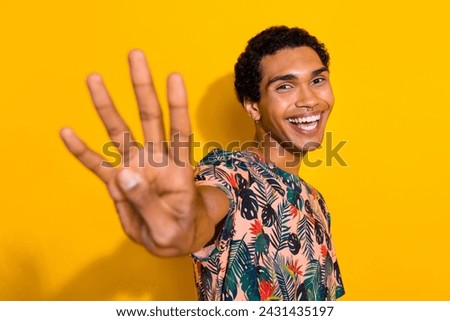 Photo of funky cheerful man wear print t-shirt showing you four fingers isolated yellow color background