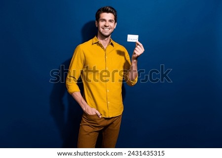Photo portrait of nice young male hold credit card banking client dressed stylish yellow garment isolated on dark blue color background