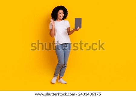 Full length photo of good mood excited lady dressed white t-shirt waving arm talking modern gadget isolated yellow color background