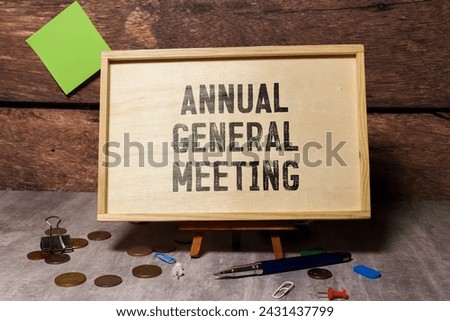 On a light background, a white notebook with are words AGM Annual General Meeting and a pen