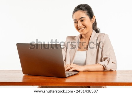 A young asian woman looks happy while working with her laptop, good vibes in office Royalty-Free Stock Photo #2431438387
