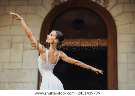 Elegant movements and gracious choreography of prima ballerina at ghosted and abandoned place. A ballet dancer is performing her art in ruined place. Art of ballet dance and ruined exterior. Royalty-Free Stock Photo #2431439799