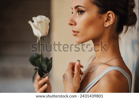 Profile of an innocent ballet dancer holding a white rose in rustic building. A fragile and gracious ballet dancer holding a white rose in abandoned place. Grace against the merciless places. Royalty-Free Stock Photo #2431439801
