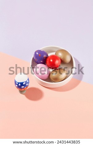 Patel color background featured a ceramic dish containing few Easter eggs in golden, red, pink and other colors. Easter poster and banner template. Copy space