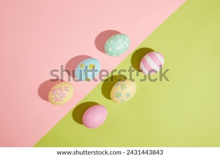 Minimal scene with top view of several beautiful Easter eggs painted in different colors and patterns arranged in two lines. The background is divided into two colors for Easter Day content