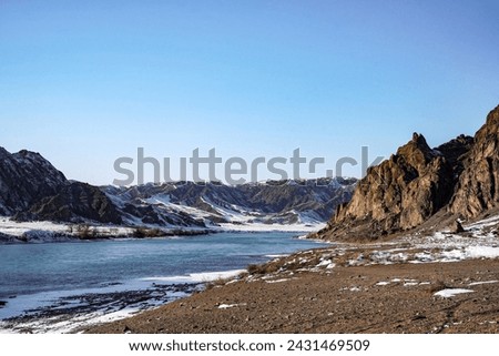 
The river froze, forming an icy panel that stretches between the rocks, like a silver bridge connecting the inaccessible cliffs on both sides. Royalty-Free Stock Photo #2431469509