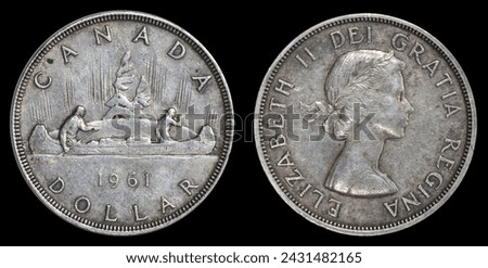 1961 silver Canadian dollar coin featuring VOYAGEUR canoe used from 1935-1986 on obverse and Queen Elizabeth on reverse. Isolated on black background. Royalty-Free Stock Photo #2431482165