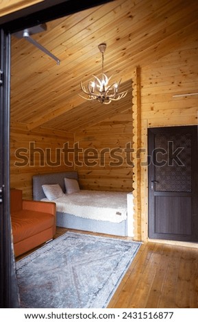 The cabins interior is paneled with wood and furnished with a bed, sofa, and armoire. A bearskin rug adds a touch of warmth to the space. Royalty-Free Stock Photo #2431516877
