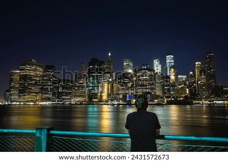 A Young Man watching the View of Manhattan Skyline from Brooklyn at Night - New York City, USA